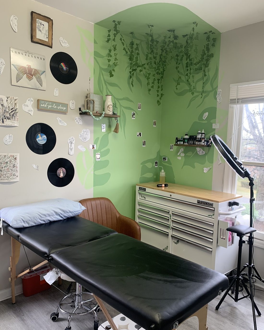Inside the Keys Tattoos private studio, with a hand-painted botanical wall mural, vinyl records and a tattoo bed